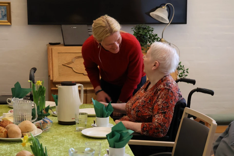 Ældreministeren, der snakker med en ældre borger i kørestol